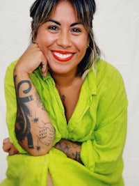 a smiling woman in a green shirt with tattoos